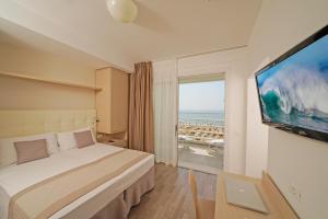 リド・ディ・イエゾロにあるHotel Strand a frontemareのベッド1台、薄型テレビが備わるホテルルームです。