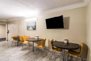 uma sala de espera com mesas e cadeiras e uma televisão de ecrã plano em Quality Inn em Pensacola