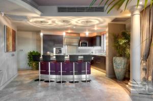 a kitchen with a bar with purple chairs in it at Radisson Blu Resort & Spa, Malta Golden Sands in Mellieħa