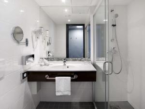 biała łazienka z umywalką i prysznicem w obiekcie Radisson Blu Hotel Lietuva w Wilnie