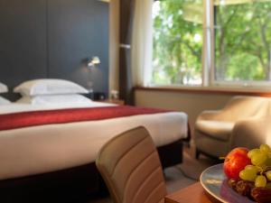 una camera d'albergo con letto e tavolo con piatto di frutta di Royal Garden Hotel a Londra