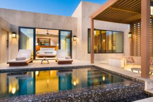 a swimming pool in a villa with two chairs at Alila Hinu Bay Salalah Mirbat in Salalah