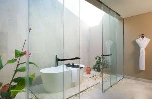 a bathroom with a tub and a glass shower at Alila Hinu Bay Salalah Mirbat in Salalah