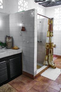 y baño con ducha y cortina de ducha. en Tichi Villas - Diani Beach, en Diani Beach