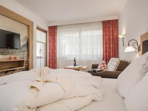 a bedroom with a white bed and a living room at Hotel Garni Larcherhof in Mayrhofen