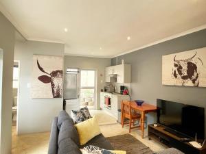 uma sala de estar com um sofá, uma televisão e uma cozinha em Alon Cottage em Joanesburgo