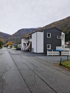 a house on a street with mountains in the background at Hillegård in Lærdalsøyri