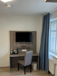 Habitación con escritorio, TV y silla. en Hotel Villa am Paradies en Jena