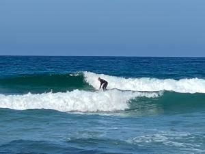 a man riding a wave on a surfboard in the ocean at Cairnvillas - Le Maquis C34 Luxury Villa with Private Pool near Beach in Aljezur