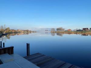 een grote hoeveelheid water met een dok en huizen bij B&B Ganzendiep aan het water in Grafhorst