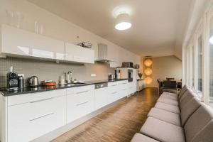 a kitchen with white cabinets and a couch in a room at Ruhige Dachwohnung mit Terrasse Berlin MITTE - Spacious modern rooftop loft in Berlin MITTE in Berlin