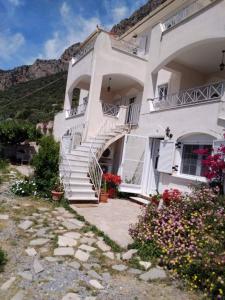 a white building with stairs and flowers in front of it at West Red Rock and View Leonidio maisonette studio in Leonidion