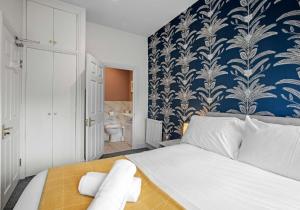 a bedroom with a bed with a blue and white wallpaper at The Narrow House - Free Parking By My Getaways in Brighton & Hove