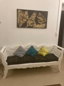 a white couch with colorful pillows sitting under a painting at Villa les Palmiers in Les Trois-Îlets