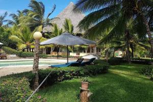 a resort with a pool and an umbrella and a chair at Baharini Beachfront Cottage in Malindi
