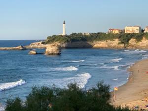 a view of a beach with a lighthouse in the distance at Biarritz centre bel Apt 2 pièces rue calme in Biarritz