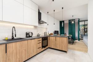 a kitchen with wooden cabinets and a living room at Kraków Rynek Podgórski Apartments by Renters in Krakow