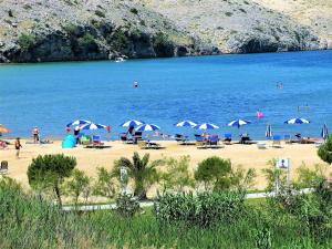 a beach with umbrellas and people in the water at Apartments by the Sea in Lopar