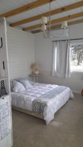 ein Schlafzimmer mit einem großen weißen Bett mit einem Fenster in der Unterkunft Los pinares in Santa Clara del Mar