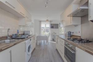 a large white kitchen with a sink and a dishwasher at 52 Molyneux Place - 5 Bedroom House in Peterborough Ideal for Groups and Families in Peterborough