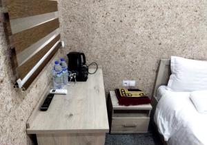 a room with a desk with a phone and a bed at Taxtapul Hotel in Tashkent