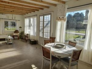 ein Esszimmer mit Tisch und Stühlen und Fenstern in der Unterkunft Los pinares in Santa Clara del Mar