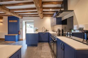 uma grande cozinha com armários azuis e um lavatório em The Hophouse em Hereford