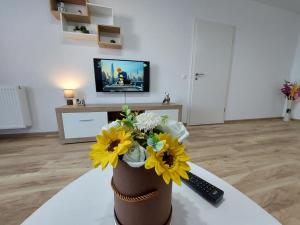 eine Vase mit gelben Blumen auf einem Tisch im Wohnzimmer in der Unterkunft Apartment Altipiani Panoramic Silver in Braşov