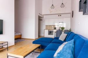 a living room with a blue couch and a kitchen at Apartament Piaski in Sarbinowo
