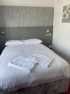 a white bed with two towels on top of it at South Fork Guest House in Leicester