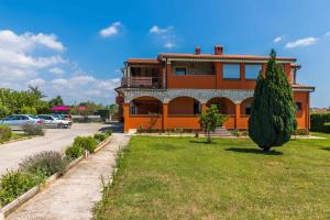 a large orange house with a tree in front of it at Apartment Pula, Istria 3 in Veli Vrh