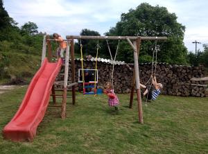 two children playing on a swing set in a yard at Jazdecký areál Budička in Trnie