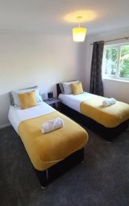 Zimmer mit 2 Betten, gelber Bettwäsche und einem Fenster in der Unterkunft Peaceful 4 bedroom house with free parking in Frimley