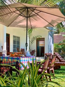 eine Terrasse mit einem Tisch und Stühlen mit einem Sonnenschirm in der Unterkunft Inn Sea Horizon Ahungalla in Ahungalla