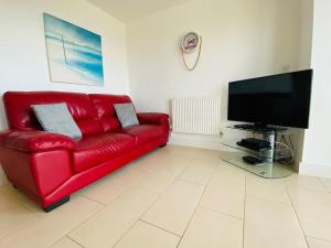 a red couch in a living room with a flat screen tv at Quayside Apartment - Large and Spacious Duplex in Castletown