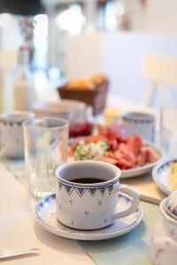 eine Tasse Kaffee auf einem Tisch mit einem Teller Essen in der Unterkunft Weissenbacherhof B&B in Oslip