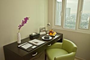 a desk with a green chair and a vase of flowers at The Exchange Regency Residence Hotel Managed by HII in Manila