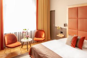 a bedroom with a bed and two chairs and a table at Hotel Elba am Kurfürstendamm - Design Chambers in Berlin