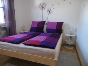 um quarto com uma cama com almofadas roxas e roxas em Lissy`s Ferienwohnung em Bad Königshofen im Grabfeld