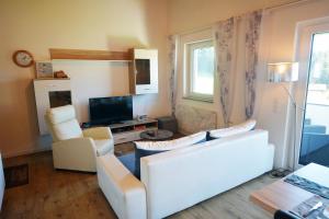 ein Wohnzimmer mit einem weißen Sofa und einem TV in der Unterkunft Ferienappartement Rettenschöss in Rettenschöss
