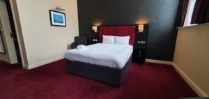 a bedroom with a large bed with a red headboard at The John Francis Basset Wetherspoon in Camborne