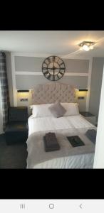 a bedroom with a large bed with a clock on the wall at The Coastal Inn in Cellardyke