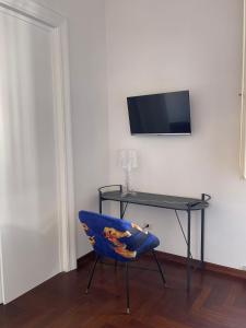 une chaise bleue assise devant un bureau avec une télévision dans l'établissement LUCIANO MONTI APARTMENT, à Rome