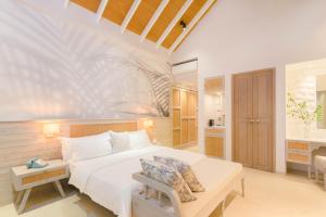a bedroom with a large bed and a bathroom at Malahini Kuda Bandos Resort in North Male Atoll