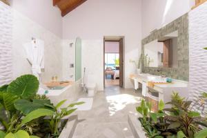 a bathroom with two sinks and a tub and a toilet at Malahini Kuda Bandos Resort in North Male Atoll