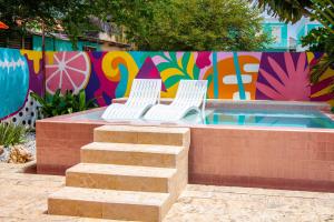 twee witte stoelen naast een muur met graffiti bij Wynwood Boutique Hotel in Willemstad