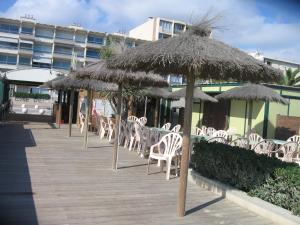 a group of chairs and umbrellas on a boardwalk at Studio vue sur la mer au 6ème et dernier étage in Canet-en-Roussillon