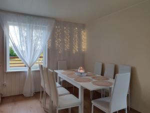 uma mesa de jantar branca com cadeiras brancas e uma janela em Ilvese Cottage Lintsi jõe kaldal 