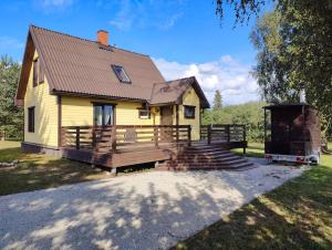 uma pequena casa amarela com um alpendre de madeira e escadas em Ilvese Cottage Lintsi jõe kaldal 