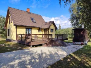 una pequeña casa amarilla con porche de madera y escaleras en Ilvese Cottage Lintsi jõe kaldal, en Änari